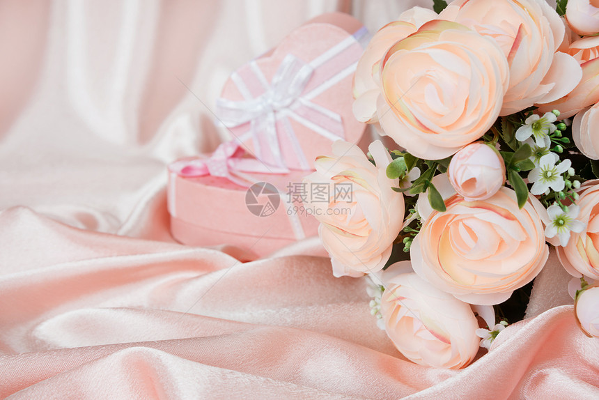 粉红骆驼花和两个心形的礼物盒在粉红丝织物背景上用白弓和粉红丝织物并有复制空间图片