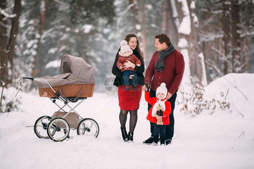 夫妇两推着婴儿车带着孩子雪地合影图片