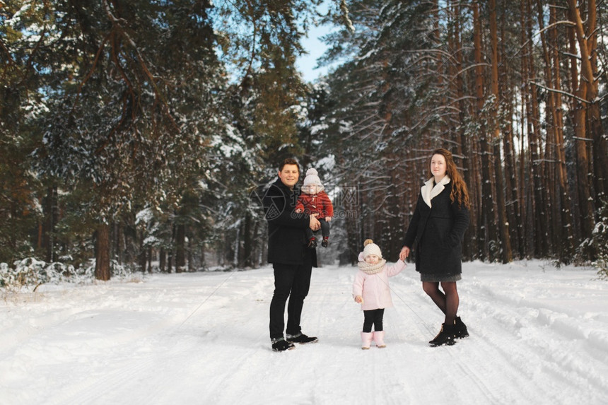 父母亲女儿和小子在冬季森林中图片