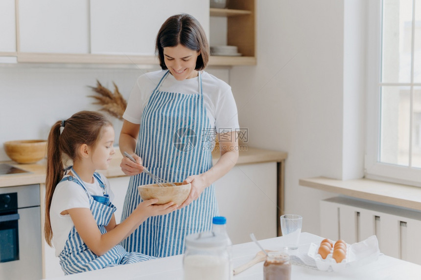 可爱女儿和妈妈一起做饭享受家庭气氛图片