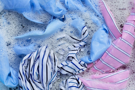 彩色衣服的顶部视图浸泡在粉末洗涤水溶解中衣夹高清图片素材