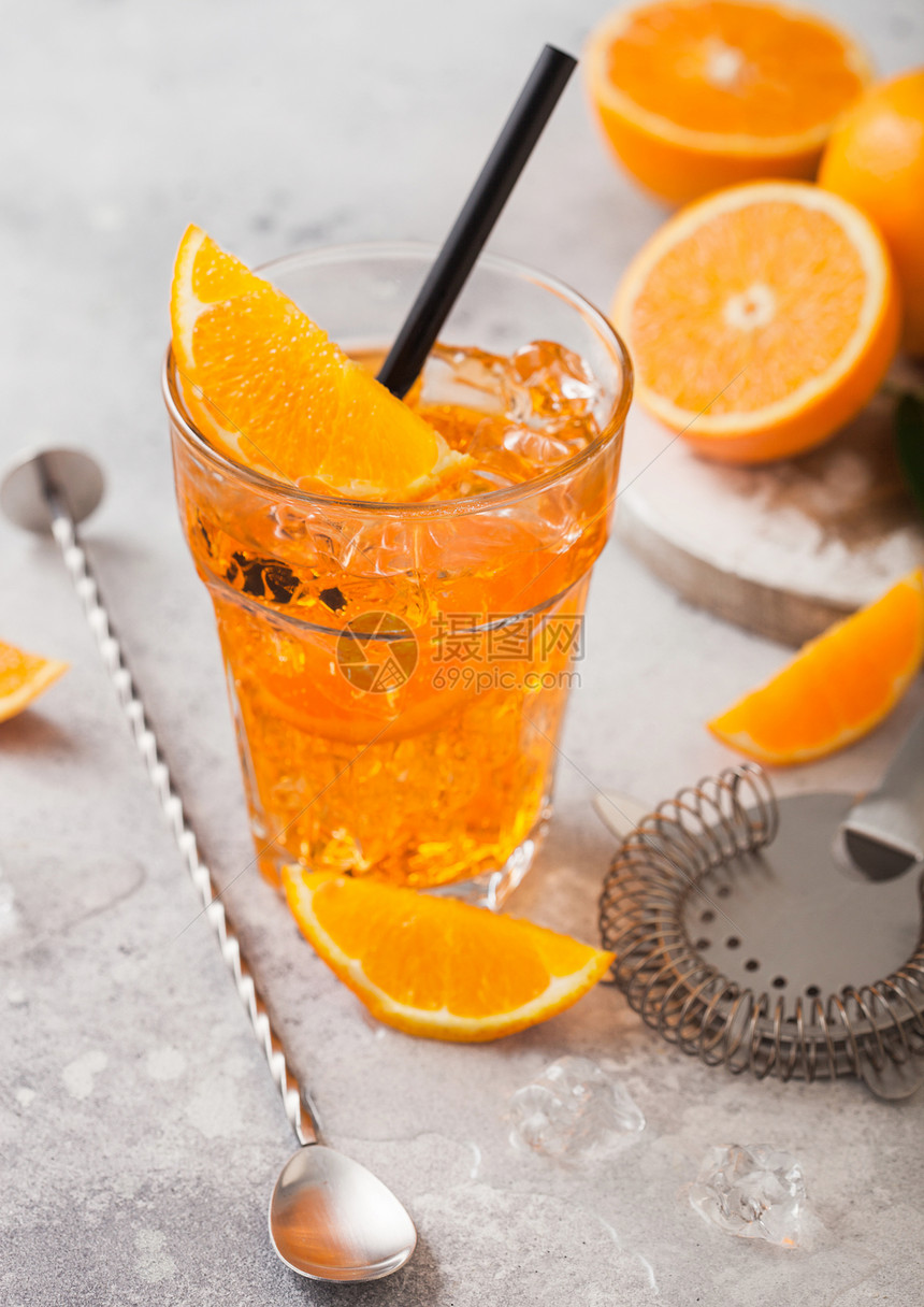 在高球玻璃中用橙子和调酒机在浅色桌底背景上用巴勺高球杯鸡尾酒图片