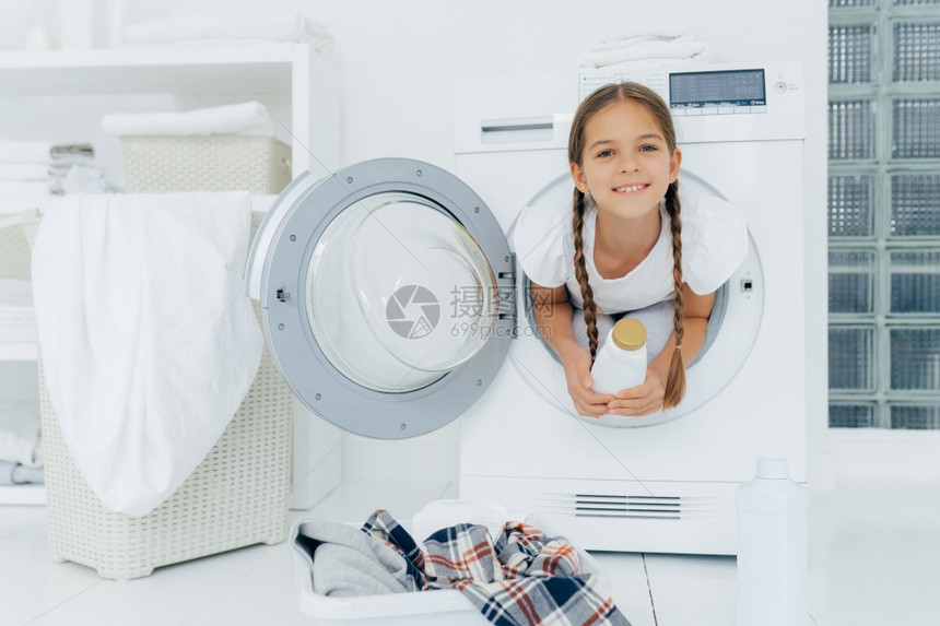 小女孩有乐趣和洗衣机里面摆姿势图片
