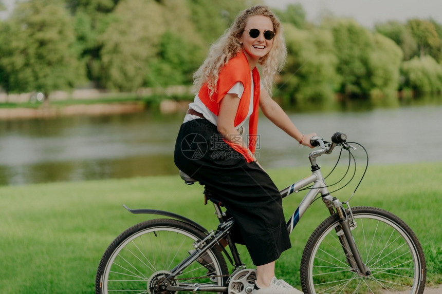 年轻女子骑着运动自行车在河道路边图片