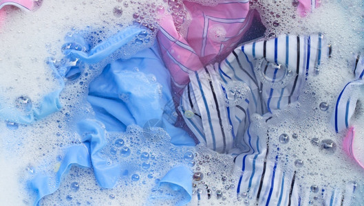 彩色衣服的顶部视图浸泡在粉末洗涤水溶解中手高清图片素材
