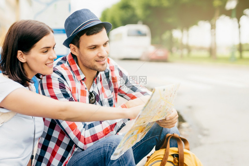 年轻男女坐在长椅上途穿越大城市休息一分钟看着指向或没有到过的地方图片