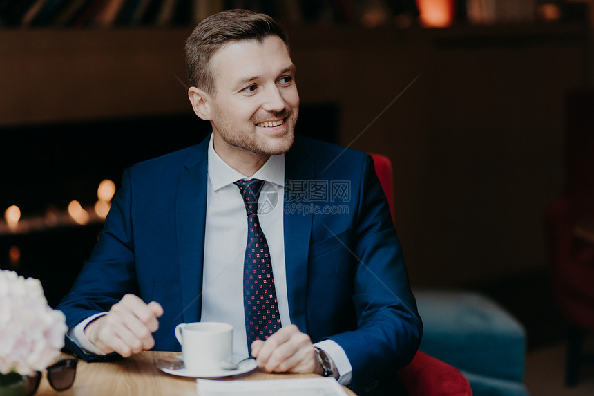 穿着正式服装的男工人快乐愉地抛在一边喝着热辣的香咖啡乐于注意到有人站在一边坐餐厅面带愉快的笑容图片