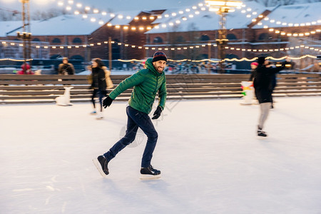 滑冰表情喜悦的胡须男子在冰环上滑有快乐的表情笑快乐的以他专业精神为恶魔身穿绿色夹克的活跃运动男子去参加冬季运动背景