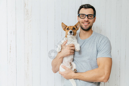 穿着临时T衬衫眼镜拥有最爱宠物站在白色木背景和空白间的对面背景图片