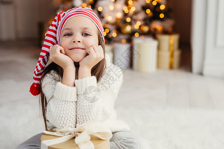 可爱的小孩横向肖像靠着手这个盒子坐在受装饰的圣诞树旁边图片