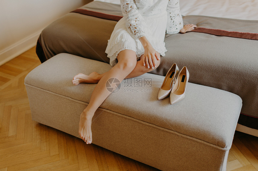 穿着白裙子的妇女光着脚坐在舒适的沙发上下班后在家休息图片