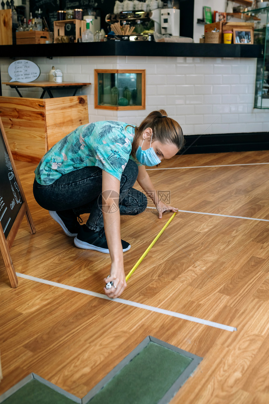 咖啡店工人测量地板标记以保持社会距离咖啡店工人测量地板标记图片