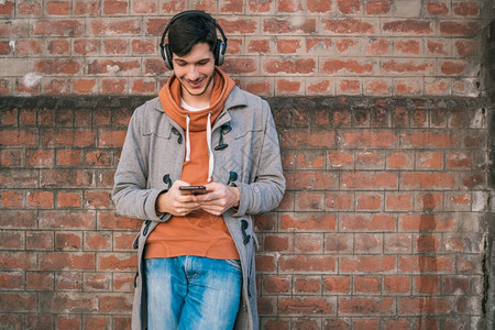 年轻拉丁男子使用手机在街上户外拍摄的肖像快乐高清图片素材