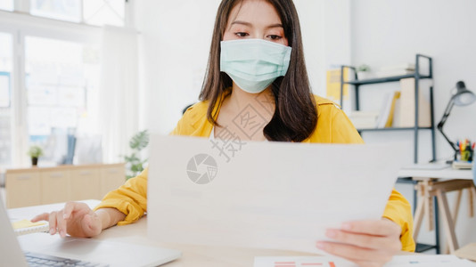 身着医疗面罩的女商人在新正常情况下用笔记本电脑在办公室工作时图片