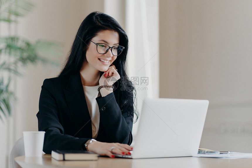 在笔记本电脑上工作远程集中微笑在设备屏幕上撰写电子邮件信函办公室饮料工作咖啡使用新的应图片