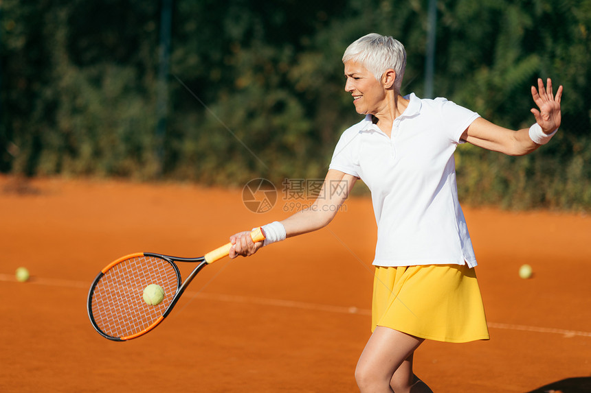 积极的成年妇女娱乐地打网球图片