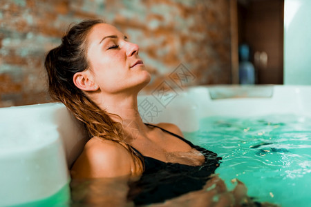 美丽的女人在温泉中心享受按摩浴缸图片