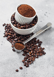 新鲜生有机咖啡豆以白碗和粉末制成以桌边背景和圆钢勺为原料背景