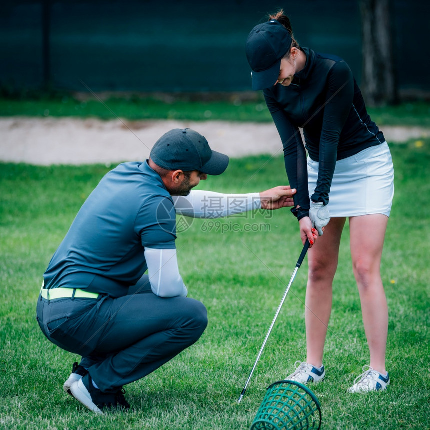 在高尔夫球场上与年轻妇女一起学习高尔夫教练图片