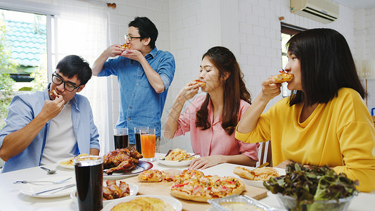 asi家庭聚会吃披萨欢笑饭坐在餐厅桌旁庆祝节假日和聚会背景图片