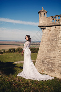 穿着结婚礼服的年轻新娘在古老城堡的背景下图片