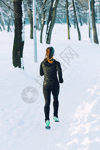 冬季女运动员在公园跑步周围下雪图片