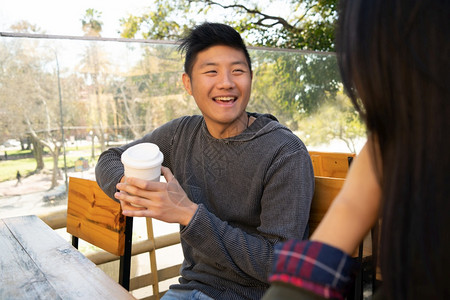 亚裔情侣开心的在咖啡店里聊天图片