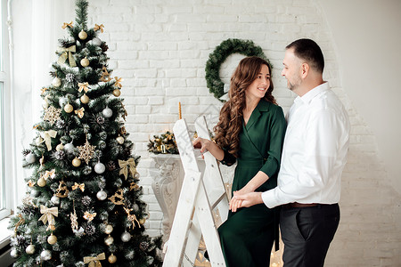 相爱的年轻夫妇在庆祝圣诞节时玩得开心一起装饰圣诞树一起装饰新年轻家庭图片