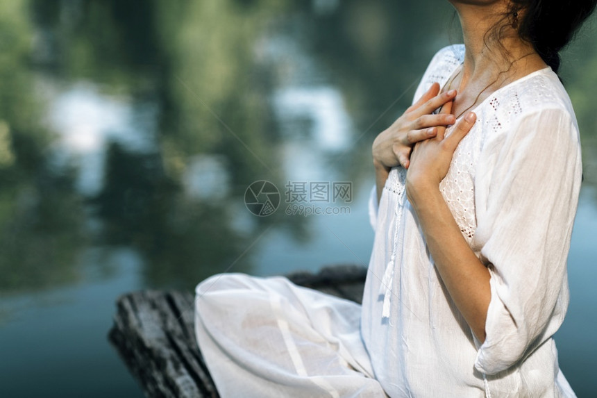 瑜伽后退宁静的年轻女子坐在莲花的位置上静地坐在湖边冥想图片
