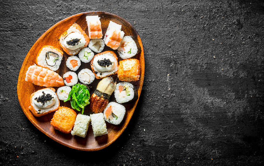 美味的寿司卷有虾蔬菜和鲑鱼在木板上有黑色生锈背景有虾蔬菜和鲑鱼在木板上图片