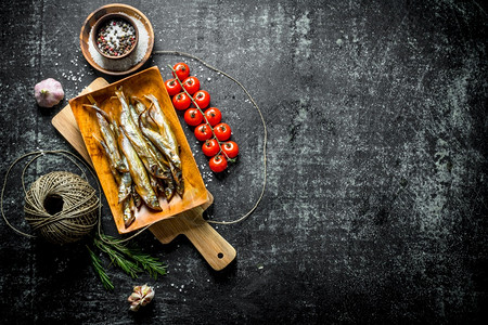 用香料西红柿和老麻绳熏鱼用黑色生锈背景熏鱼用香料西红柿和老麻绳熏鱼图片