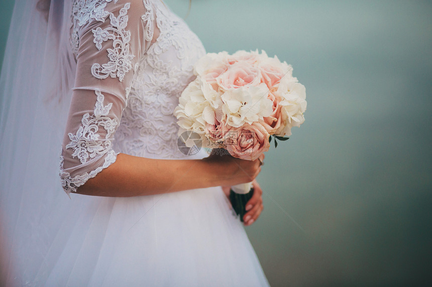新娘穿着优雅的婚纱盛着一束美丽的花朵和绿色叶子婚礼主题穿着优雅的婚纱新娘拿着一束美丽的花朵和绿色叶子图片