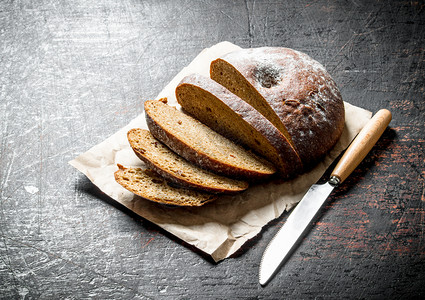 用刀子切开新鲜面包用刀子切开黑色生锈背景的新鲜面包用刀子切开新鲜面包图片