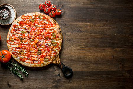配西红柿和迷迭香的比萨木制背景的比萨图片