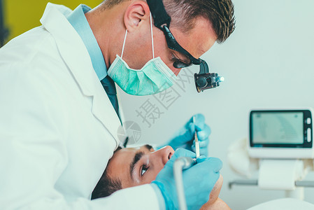 与青年男子一起工作的牙医背景图片