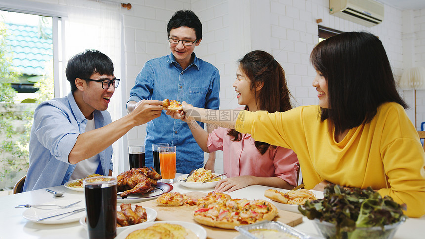 asi家庭聚会吃披萨欢笑饭坐在餐厅桌旁庆祝节假日和聚会图片
