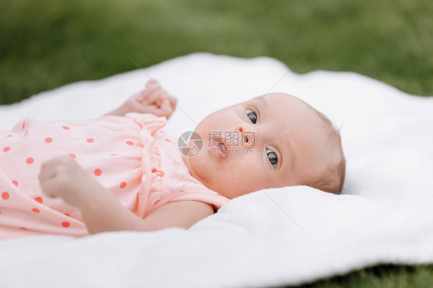 公园户外草坪上的新生女婴躺在白色毯子上图片
