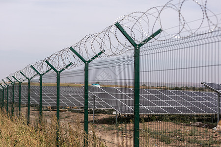 光伏替代电源可持续资源的概念现场太阳能电池板金属带刺铁丝网的围栏可持续资源的概念背景图片