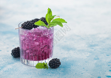 清凉的夏季鸡尾酒在晶玻璃中加黑莓有冰块和薄荷蓝底苏打汽水和酒精混合图片