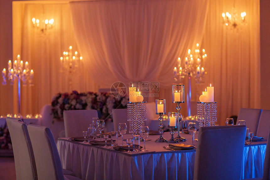 喜庆式婚礼桌用黄色灯光燃烧蜡烛水晶板块和眼镜水晶蜡烛架作为婚礼招待会的中心部分喜庆式婚礼桌作为招待会的中心部分图片