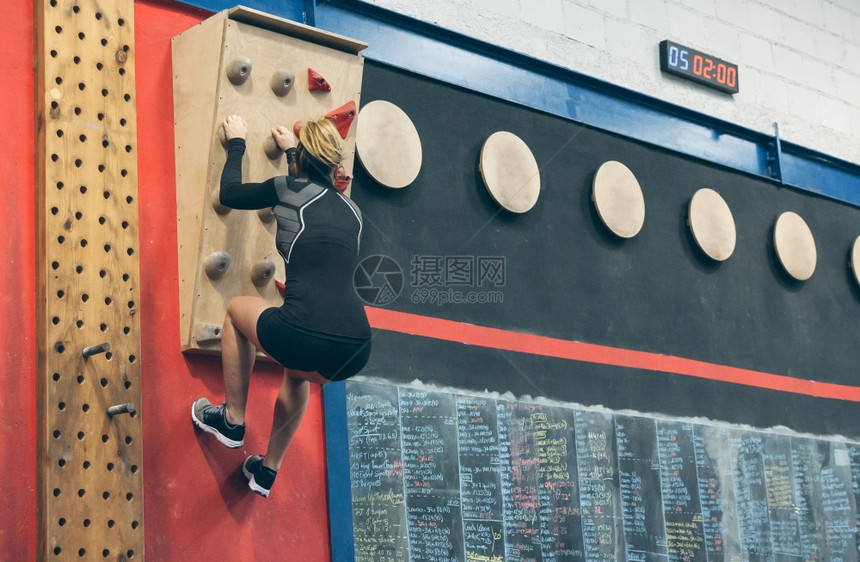 体育馆的攀爬墙上挂着女运动员培训图片