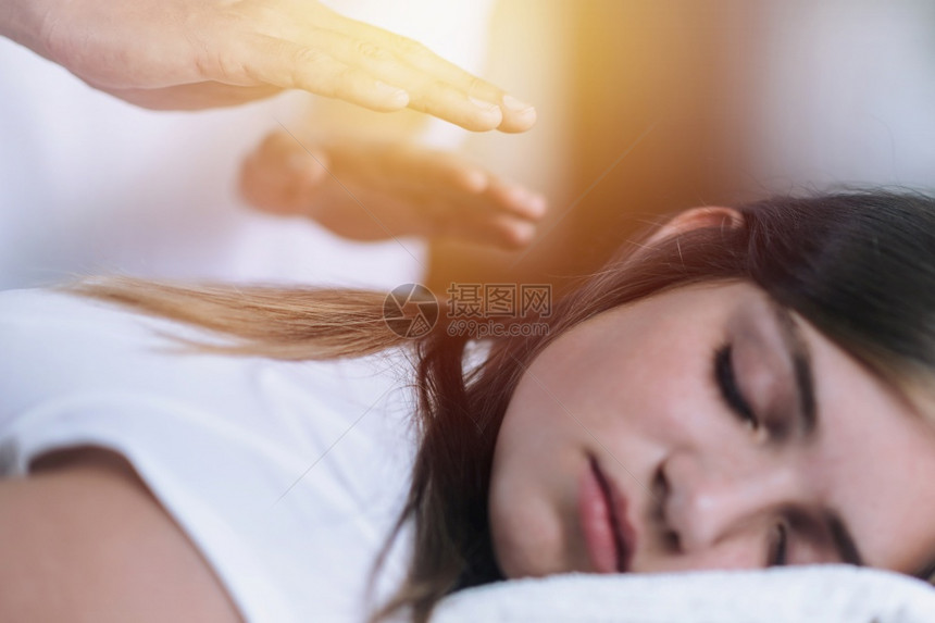 reik治疗师把病人的手伸回去转移能量和平的少女闭着眼睛躺减轻压力和放松的替代治疗概念图片