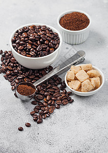 新鲜生有机咖啡豆以白碗和粉末制成以甘蔗和圆钢勺在桌边背景上背景