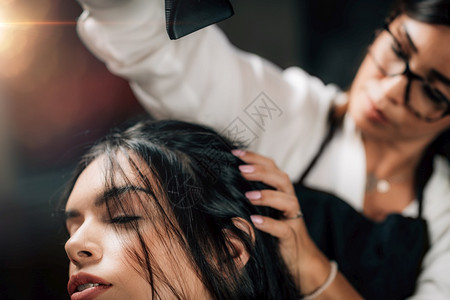 近身擦干理发师的型女人和头发在沙龙里擦干头发图片