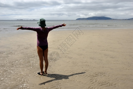 在海滩上的年轻女子张开双臂图片