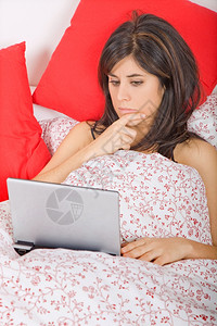在床上用笔记本电脑工作的年轻女子深色头发高清图片素材
