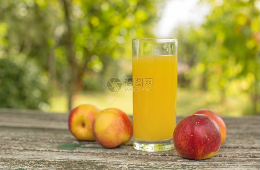 桃子和汁放在户外的木制桌上图片