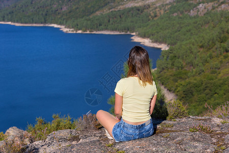 坐在山上放松和享受湖水的年轻女子在法公园Gers图片