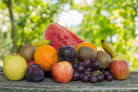 一堆西瓜葡萄木制桌边的水果户外背景