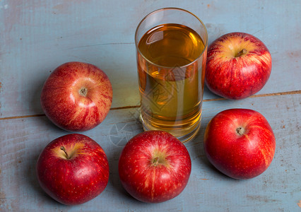 苹果汁和红在蓝色的老木头背景苹果汁图片